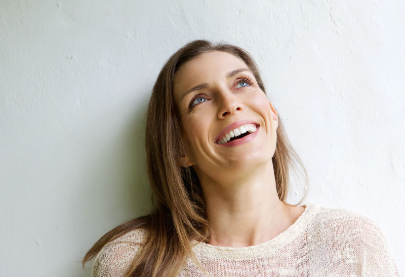 Image of an older woman with dark blonde hair smiling and looking upwards